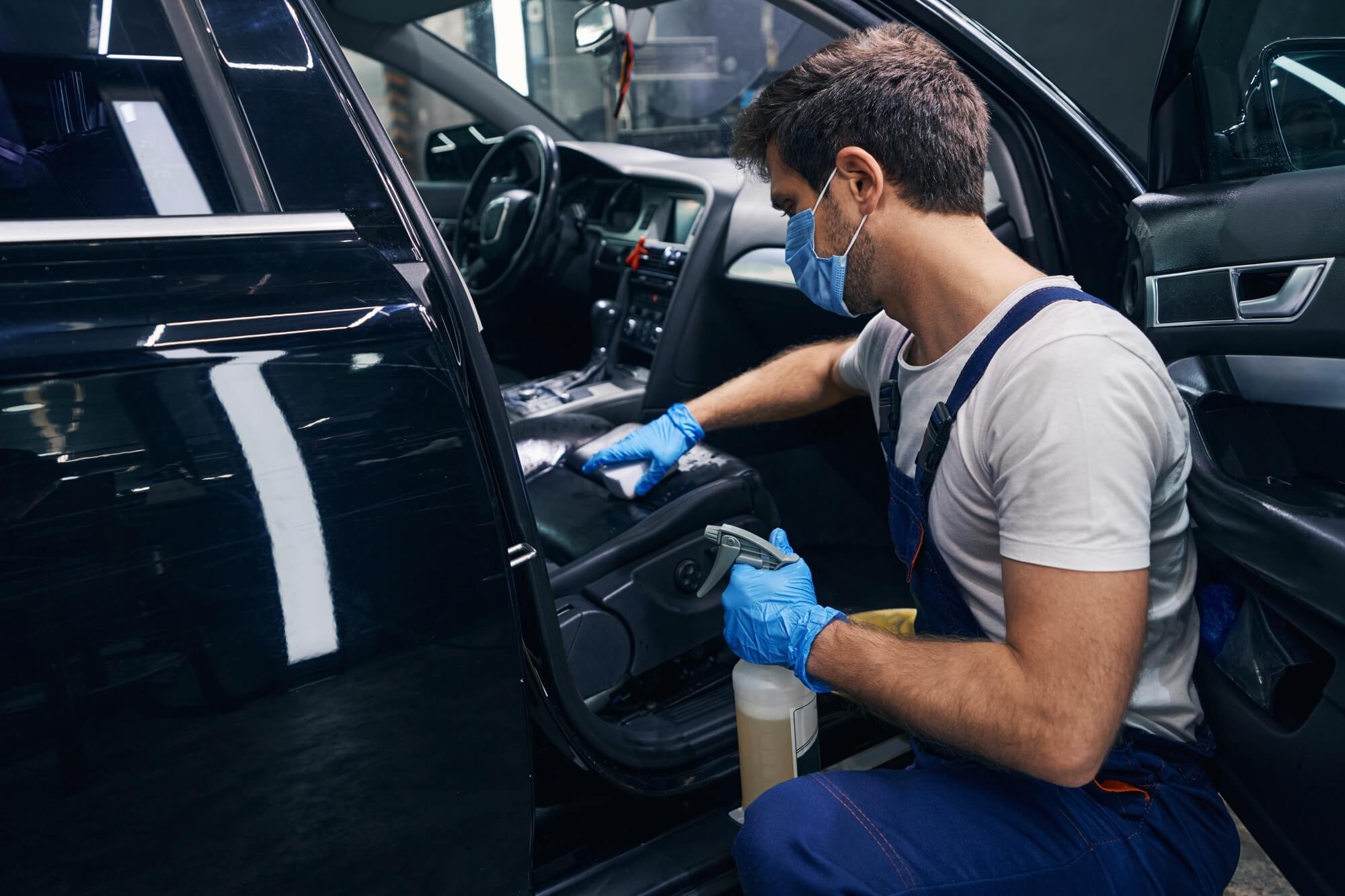 male-wiping-seat-clean-in-black-car-during-detailing.jpg